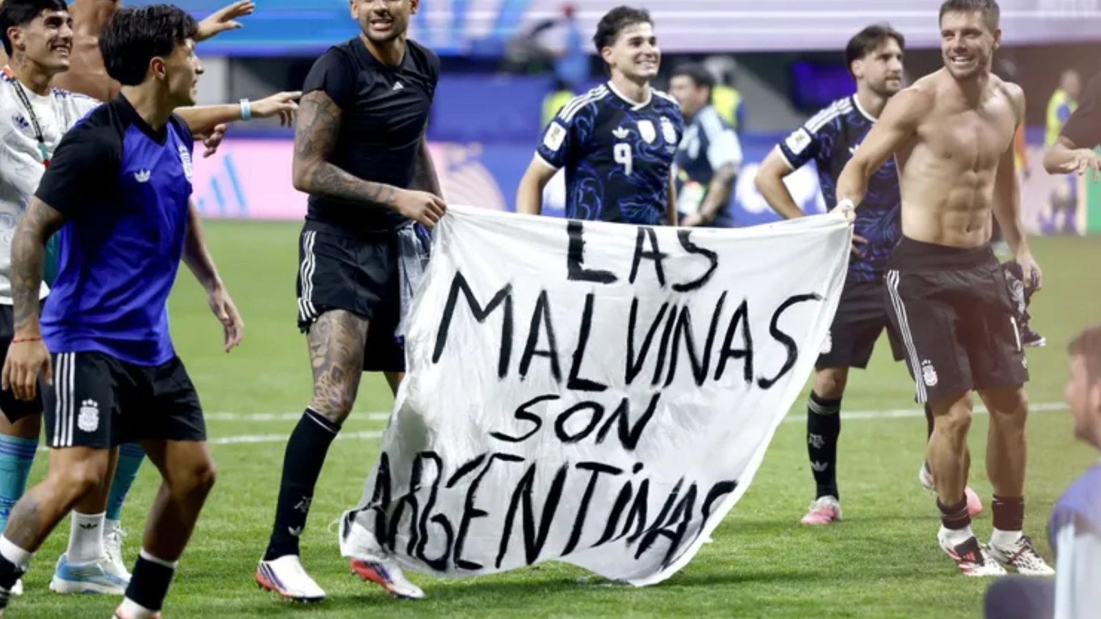 Hinchas argentinos con una bandera que dice Las Malvinas son Argentinas